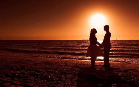 Pareja romántica en la playa durante la puesta del sol ...